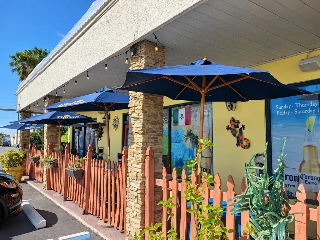 The Chicanos patio with blue umbrellas, brick columns and colorful fence